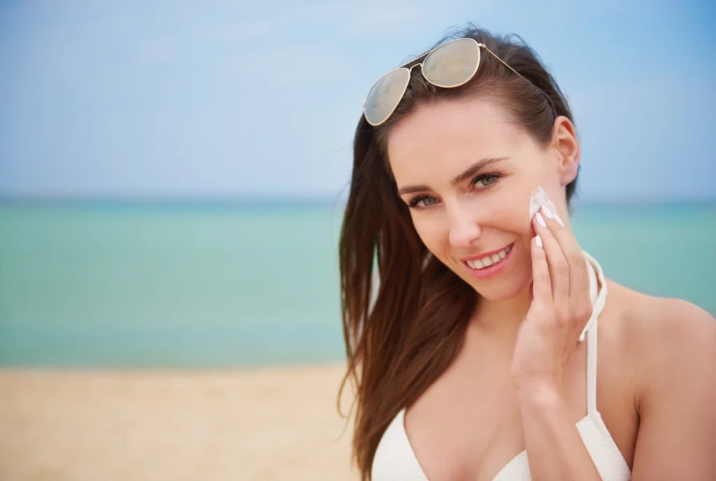 Young beautiful woman taking care of her skin on the beach